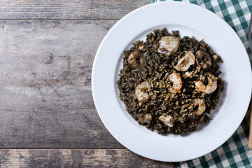 Black rice with seafood on wooden table. Top view. Copy space