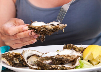Woman eat with a fork oysters. Lifestyle concept