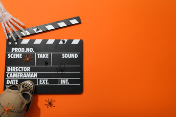 Clapperboard and Halloween decorations on orange background, space for text