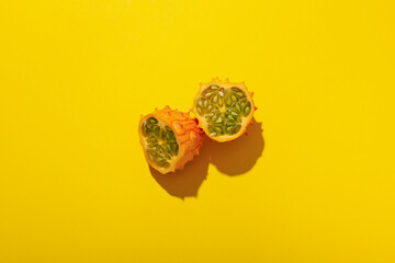 Two half of kiwano fruit on yellow background, top view
