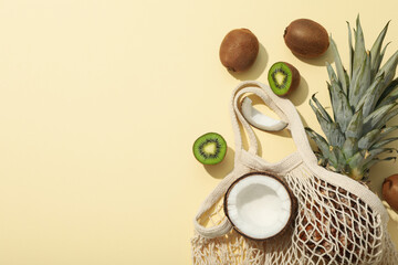 Set of tropical fruit in bag on beige background, space for text