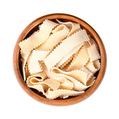 Rustiche ribbon pasta with serrated edges, in a wooden bowl. Uncooked, short thick serrated ribbons of noodles, also called laminated pasta, made of durum wheat semolina and egg. Close-up from above.