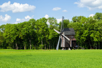 Wooden windmill in a green meadow