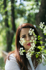 Portrait of a pretty 45 years old woman with red lips and looking at camera between flowers with...