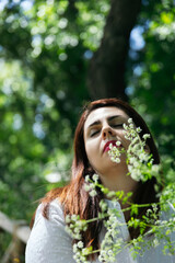 Portrait of a beautiful 45 years old woman with closed eyes relaxing and calm among flowers with...