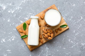 Top view of the almond milk in the glass bottle with almond nuts on the colored table. top view...