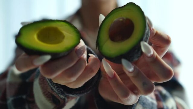 ripe avocado in the hands of a girl.
Sliced ​​avocado in hands