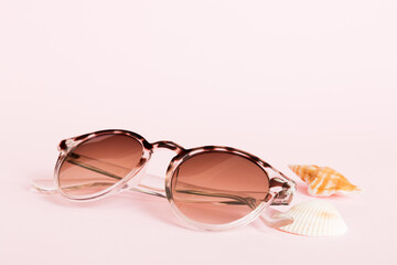 sunglasses with seashell lying on table background. Sunglasses on summer background. Top view flat...
