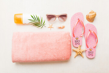 Summer holiday concept. Top view of beach towel, flip flop and sunscreen cream on table Top view...