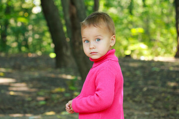 Little adorable serious girl in spring outdoors.