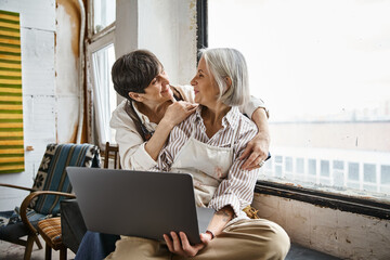 Couple on window sill engrossed in laptop.