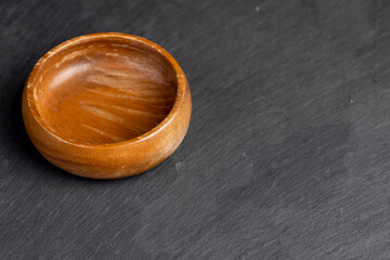 an empty wooden bowl on a black stone board