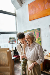 Two women, mature and in love, standing side by side in an art studio.