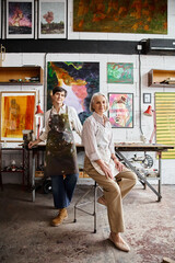 Two women admire paintings in an art studio.