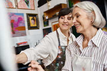 Two women, mature and in love, standing together in an art studio.