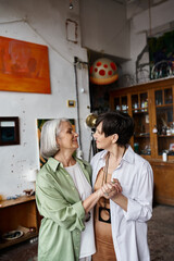 Two mature women stand together in an art studio.