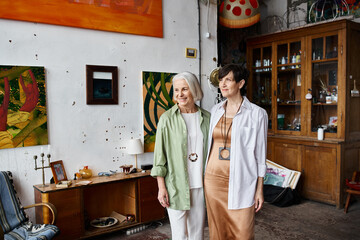 A mature lesbian couple standing united in an art studio setting.