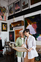 Mature lesbian couple peacefully standing together in an art studio.