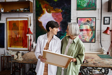 Two mature lesbian women standing in an art studio.