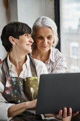 Two women engaged in work, focusing on laptop screen.