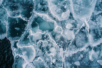 Aerial view of ice floes in a frozen sea, capturing the abstract patterns and textures formed by the ice. Emphasize the natural lines and the contrast between the white ice and the dark water.