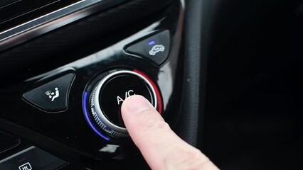 Man's hand presses round button to turn on air conditioner in car. Turning on the air conditioner in the car.
