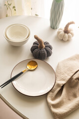 Dinner table setting with white plates and  decorative knite pumpkins on white table top view.