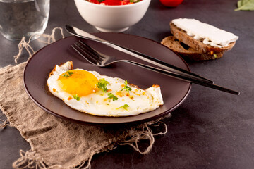 Fried eggs in broun plate with cheese sandwich and tomatoes salad  for breakfast