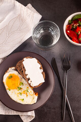 Fried eggs in broun plate with cheese sandwich and tomatoes salad  for breakfast
