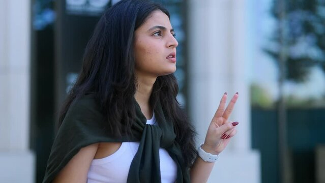Portrait of beautiful young indian woman thinks questioningly about difficult choice choose imagine plan in mind has doubts create idea with laptop computer at city centre	