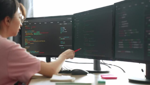 Slow motion back end software developer engineer for computer programming working together on debugging writing computing code, solving complex algorithms display on monitor in office. Burgeoning