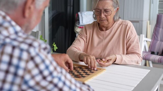 Pensioners pastime at senior home. Aged couple playing checkers. Activities for seniors, elderly active lifestyle, older people time spending concept
