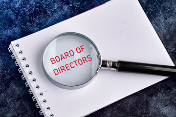 Business concept. Text BOARD OF DIRECTORS through a magnifying glass in a notebook on a beautiful...