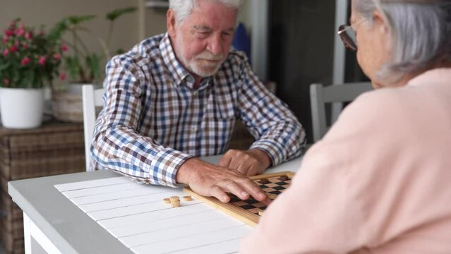 Pensioners pastime at senior home. Aged couple playing checkers. Activities for seniors, elderly active lifestyle, older people time spending concept
