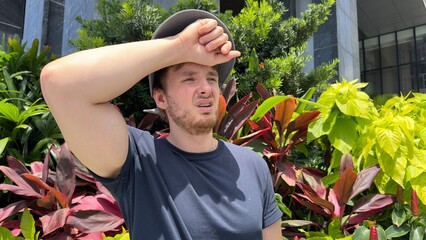 Young tired exhausted man suffering from heat, high temperature in the tropical city. dangerous...
