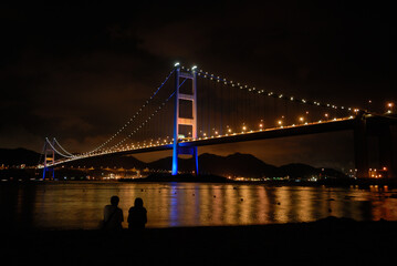 Fototapeta premium Two people under the Tsing-Ma Bridge at night