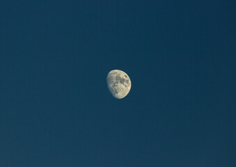 Detailed photo of the moon, more than half full, against a deep blue sky, space, lunar, astronomy, craters