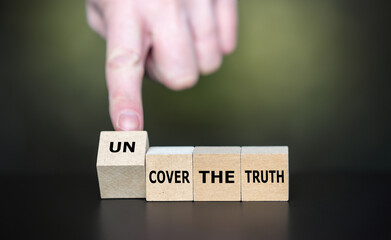 Hand turns cube and changes the expression 'cover the truth' to 'uncover the truth'.