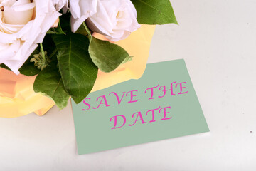 Business concept. Text SAVE THE DATE on a piece of paper near a bouquet of flowers