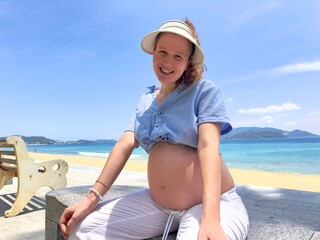 Happy pregnant young woman enjoy summer vacation on the beach, sea in tropical country