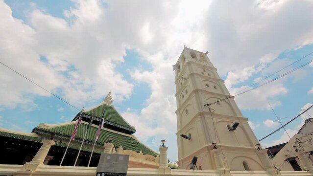 Melaka, Malaysia - 10th april, 2024: panning view Kampung Kling Mosque. Minaret and mosque facade in sunny blue sky day.