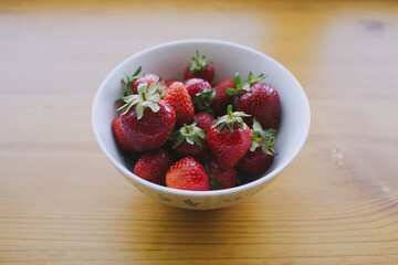 Strawberries in a bowl, close-up photo on a wooden table