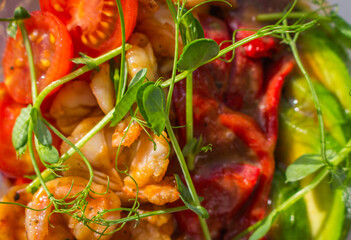 Grilled shrimps, red bell pepper with avocado and tomato in plastic bowl. Poke bowl in sunlight. Traditional asian food. Street food to go. Healthy eating concept. Seafood poke bowl with pea sprouts.