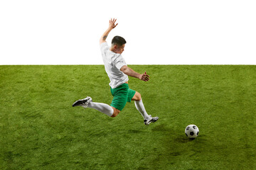Side view of soccer player in green shorts and white jersey, captured mid-kick on green grass field against a white background. Concept of professionals sport, competition, tournament, energy, action.