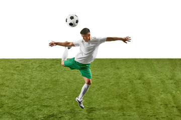 Dynamic shot of footballer showcasing powerful jump to head soccer ball on green lush field against...