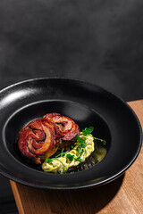 Gourmet bacon-wrapped meat and vegetables on black plate