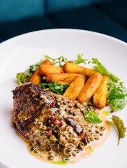 Gourmet steak with green peppercorn sauce and roasted potatoes