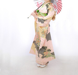 ピンクの振袖を着て和傘をさす女性