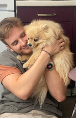 Young happy man hugging his pet Pomeranian Spitz dog
