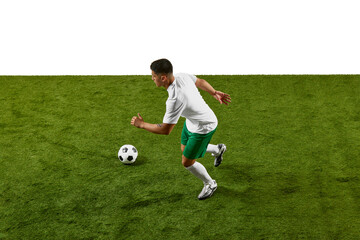 Dynamic image of athlete in green shorts and white shirt, running to strike soccer ball with force, caught mid-motion on field. Concept of professionals sport, competition, tournament, energy, action.